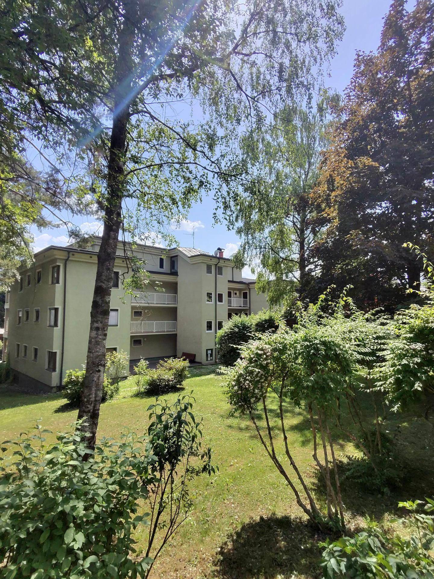 Ansicht des Mehrfamilienhauses mit mehreren Balkonen und umgebender Grünfläche.