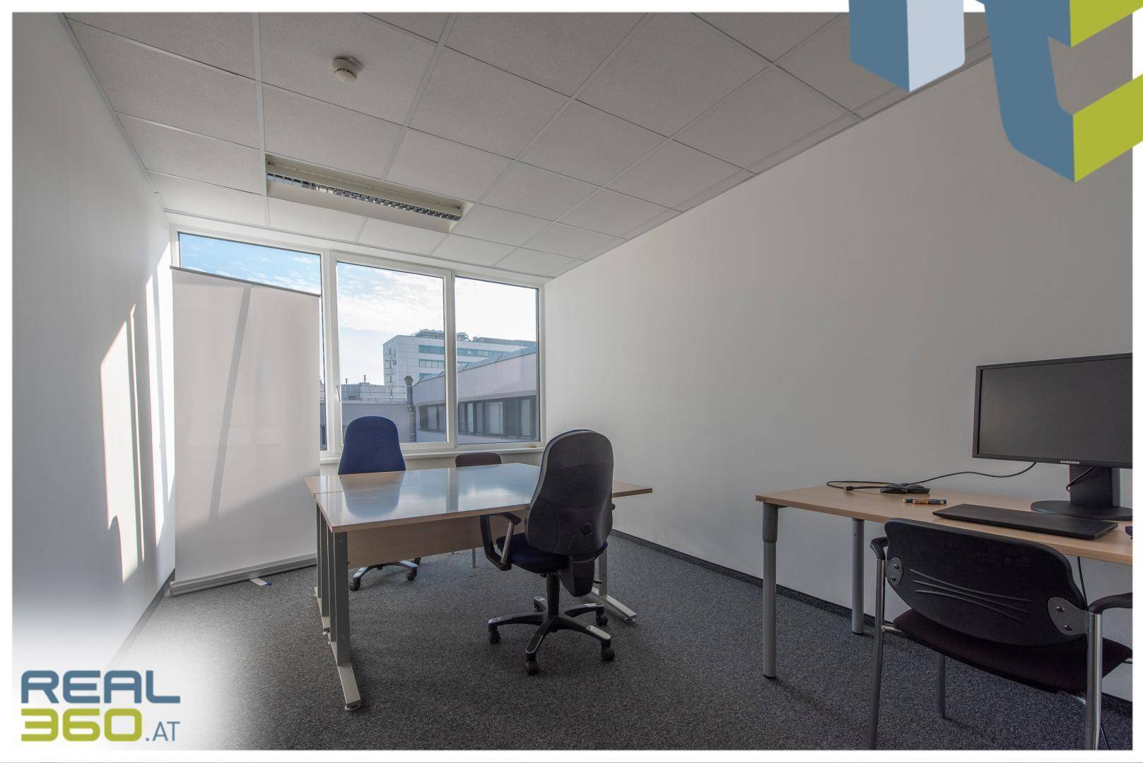 Einzelbüro mit Schreibtischen, Bürostühlen und großen Fenstern, die eine helle Arbeitsumgebung schaffen.