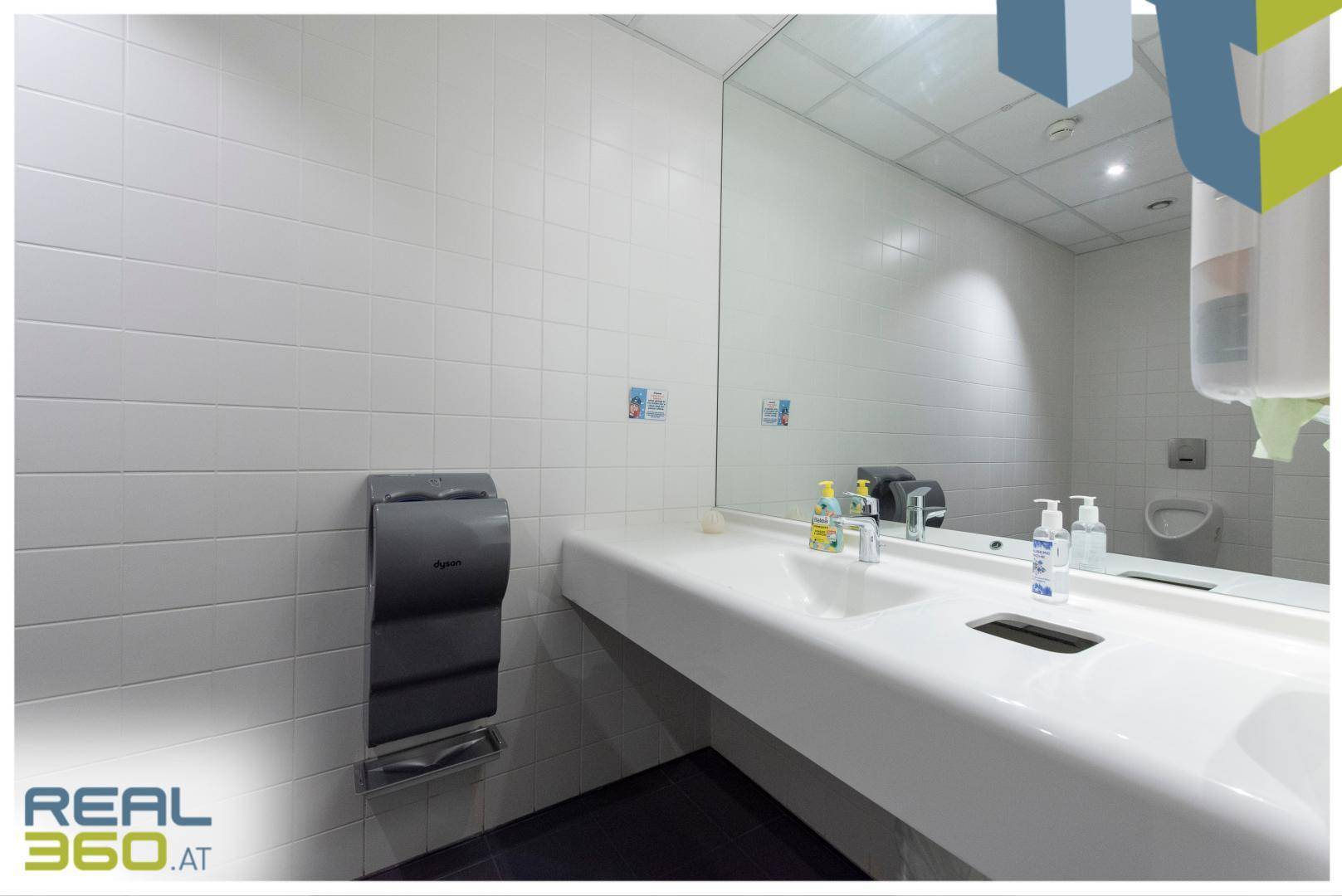 Modernes Badezimmer mit großem Spiegel, Doppelwaschbecken und weißen Fliesen an den Wänden.