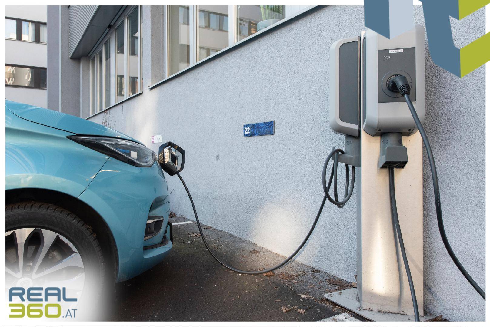 Elektrofahrzeug wird an einer Ladestation vor einem Gebäude aufgeladen, umweltfreundliche Infrastruktur.