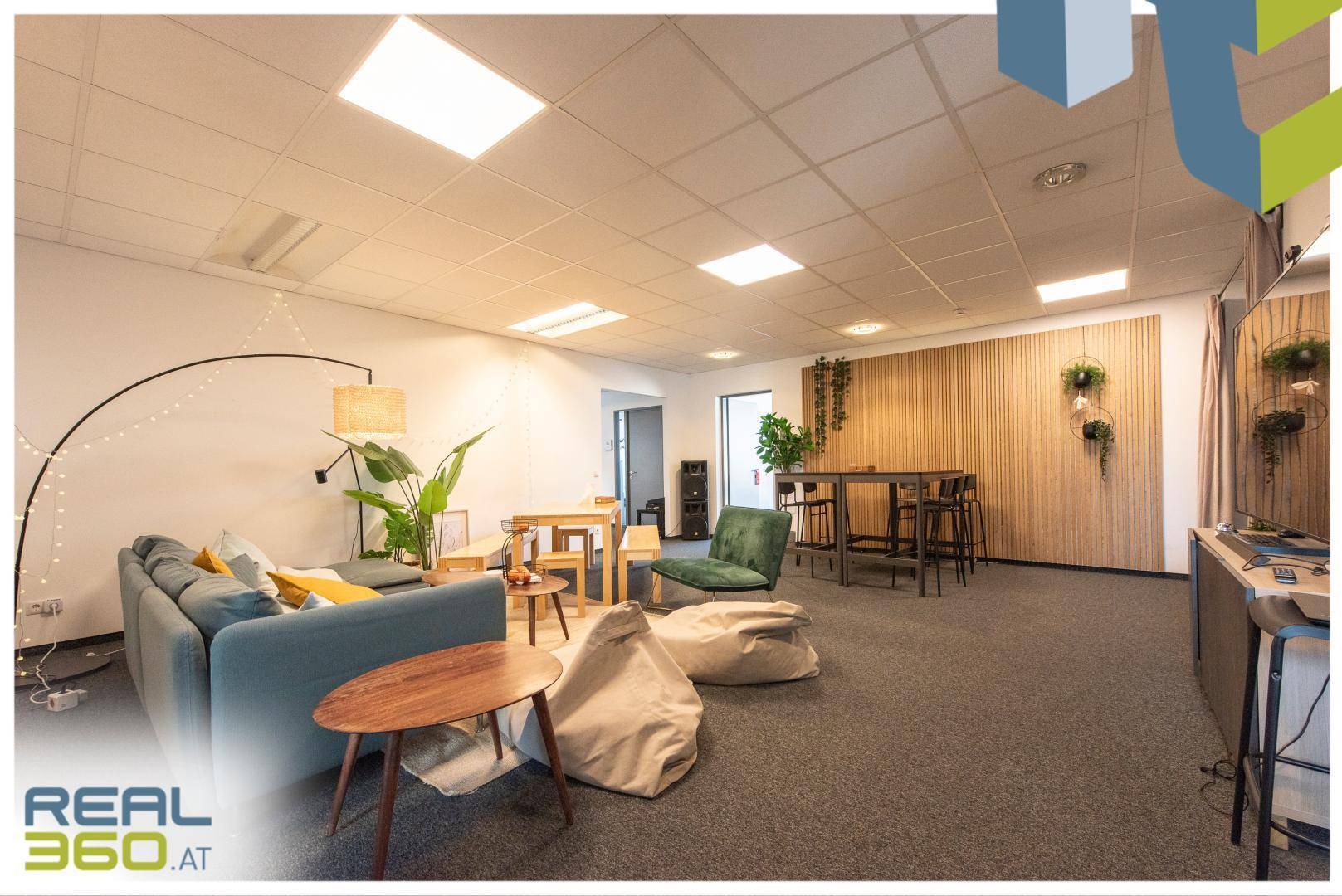Gemütlicher Loungebereich mit Sofa, Sitzsäcken und Holzwand, ideal für entspannte Pausen oder informelle Treffen.