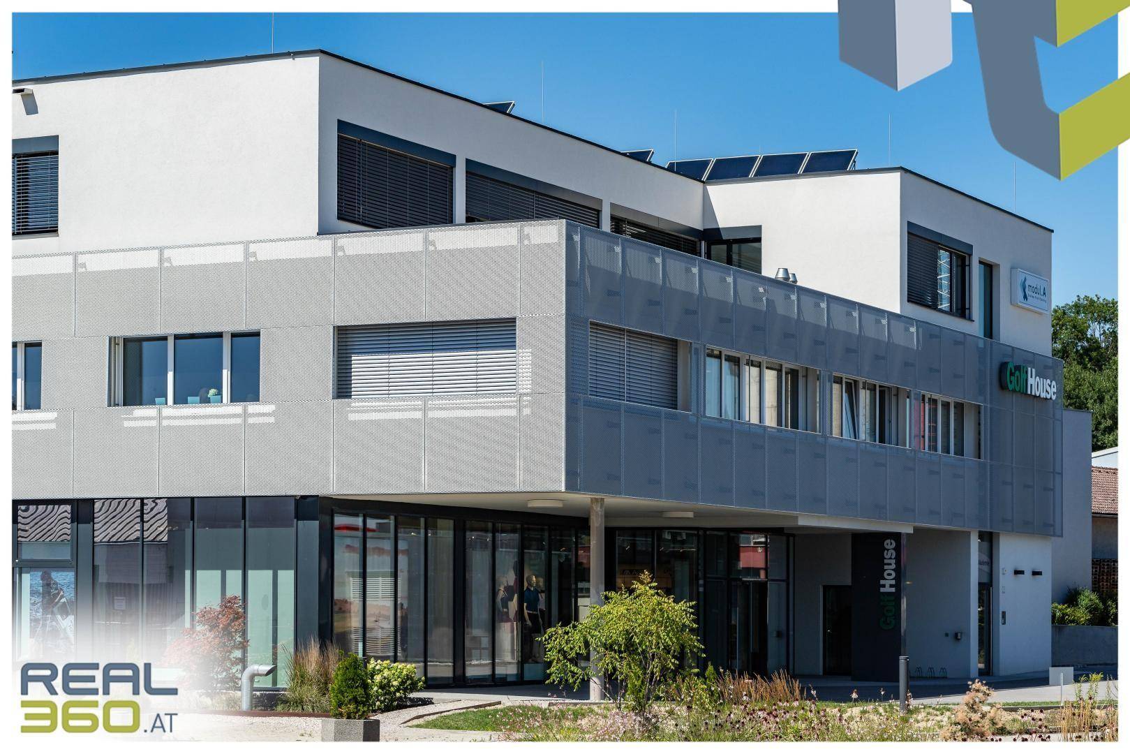 Detailansicht der modernen Fassade mit großen Fenstern, Jalousien und einem einladenden Eingangsbereich.