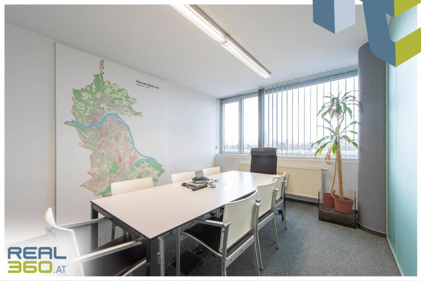 Konferenzraum mit großem Tisch, Stühlen und einer Stadtkarte an der Wand, ideal für Besprechungen und Präsentationen.