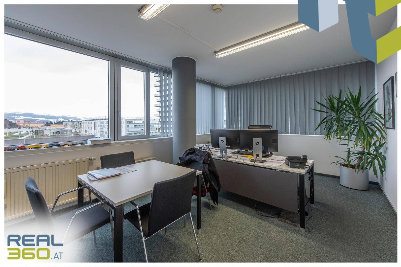 Büro mit Arbeitsplätzen, einem runden Säulenpfeiler und weitem Blick auf die Umgebung.