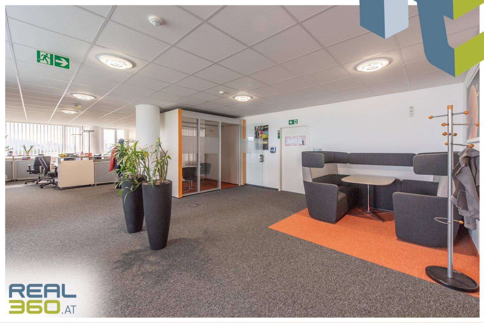 Bürofläche mit Besprechungsbereich, Teppichboden und einer gläsernen Kabine für private Gespräche.