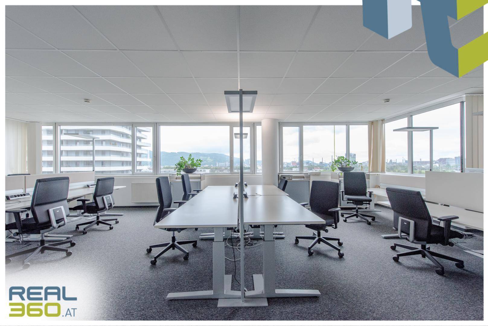 Großzügiges Großraumbüro mit vielen Arbeitsplätzen, ergonomischen Stühlen und weitem Ausblick.