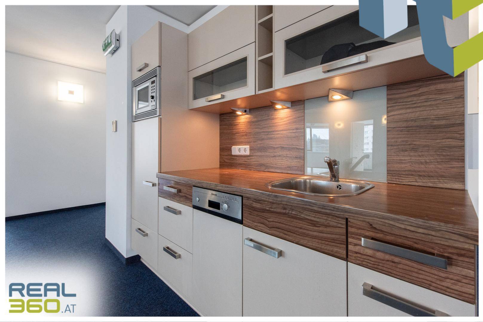 Detailansicht einer modernen Küchenzeile mit Holzoptik-Arbeitsplatte, Spüle und integrierten Geräten.