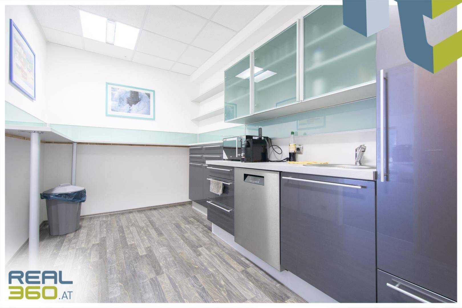 Moderne Küchenzeile mit grauen Schränken, integriertem Geschirrspüler und Holzoptik-Laminatboden.