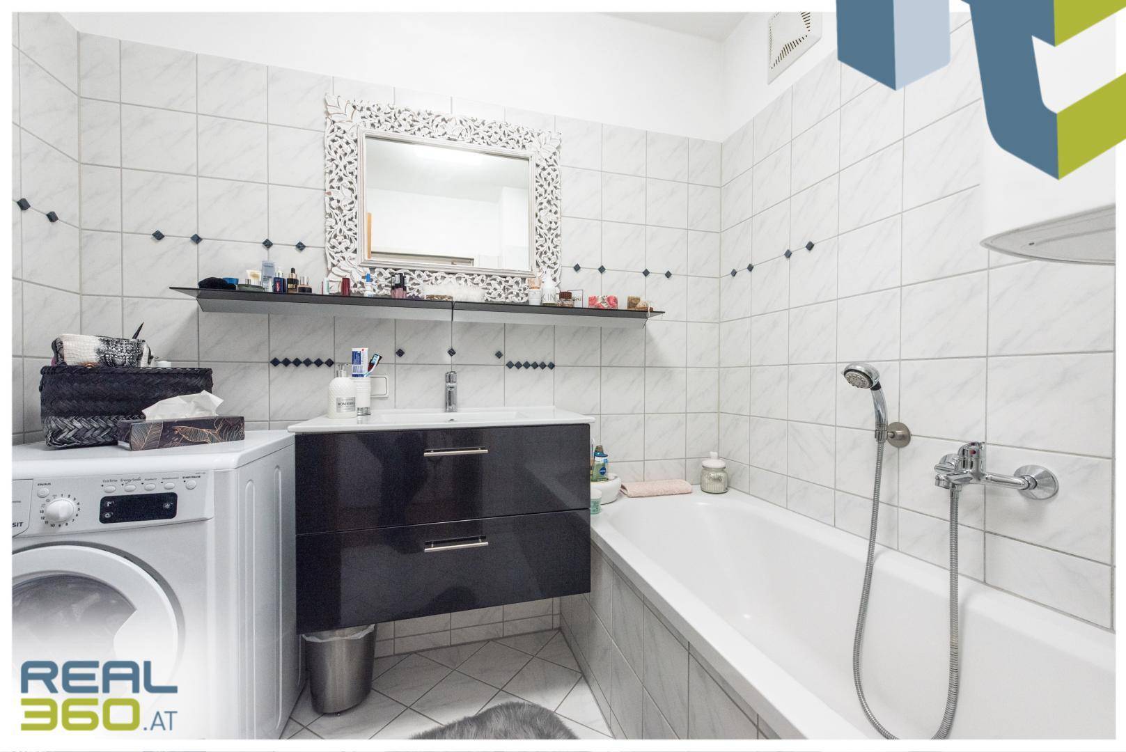 Modernes Badezimmer mit Badewanne, Waschbecken und Waschmaschine, hell gefliest.