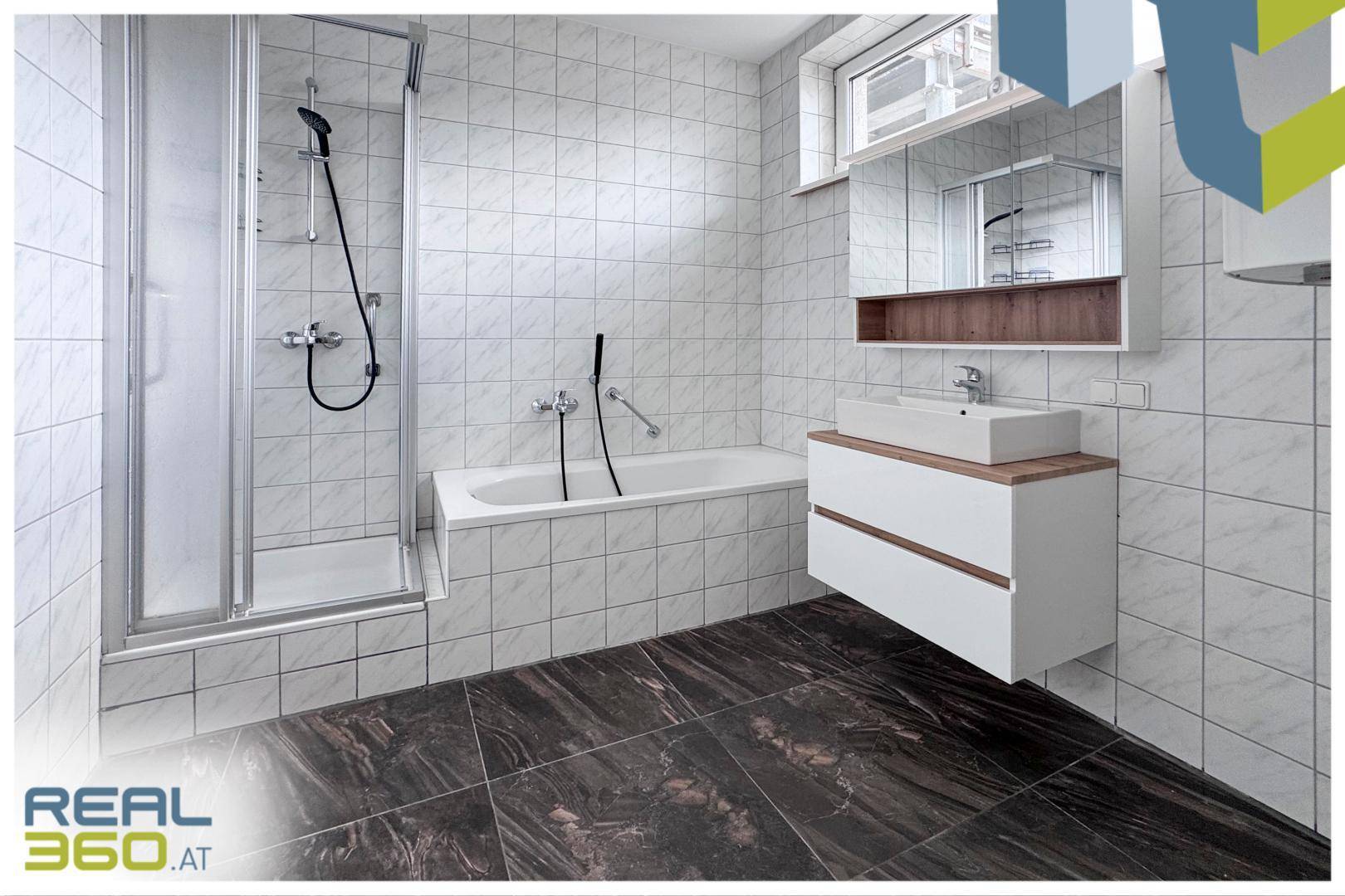 Modernes Badezimmer mit Badewanne, Duschkabine, Waschtisch und Fenster für Tageslicht.