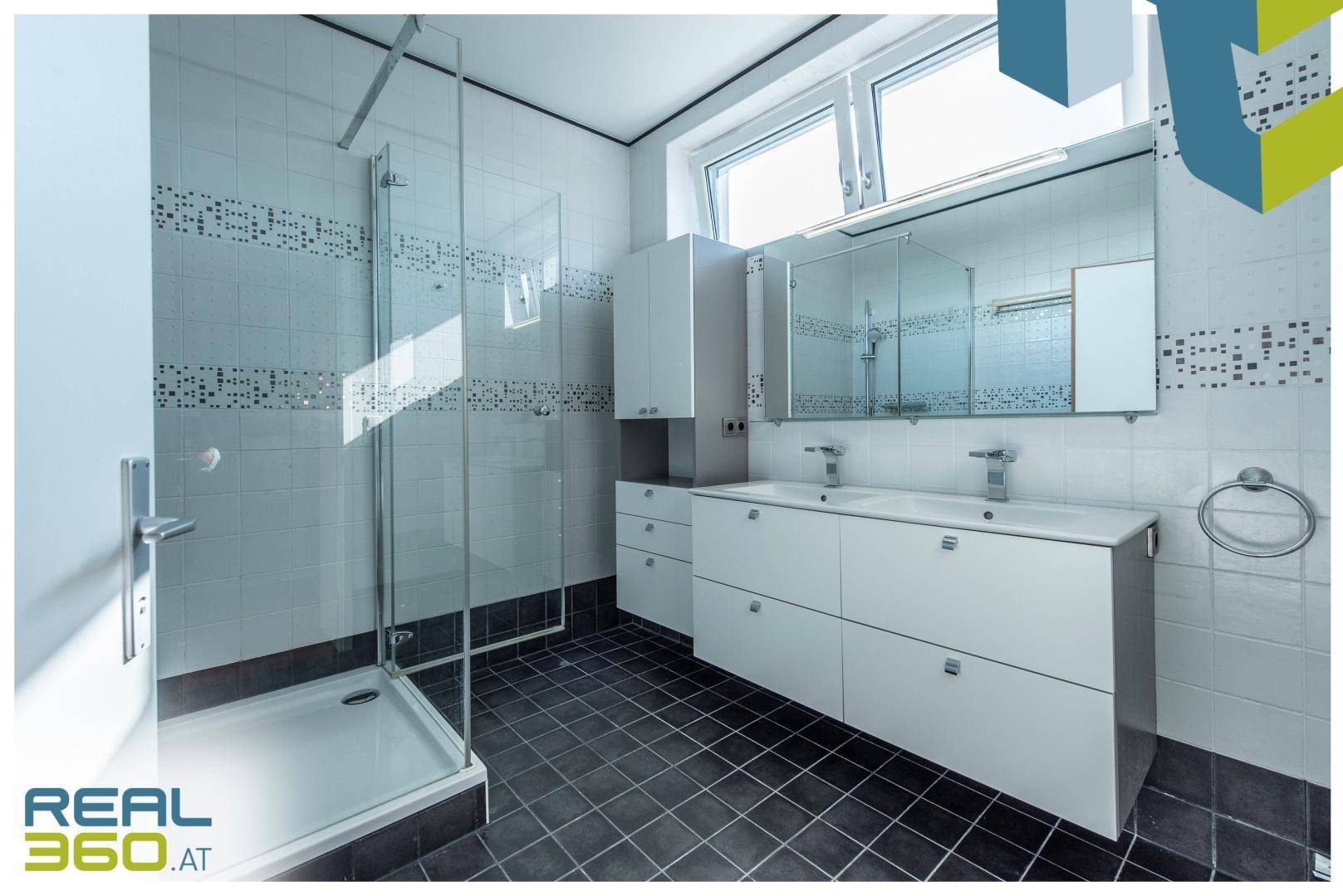 Modernes Badezimmer mit Duschkabine, Doppelwaschbecken und Fenster für natürliche Belüftung.