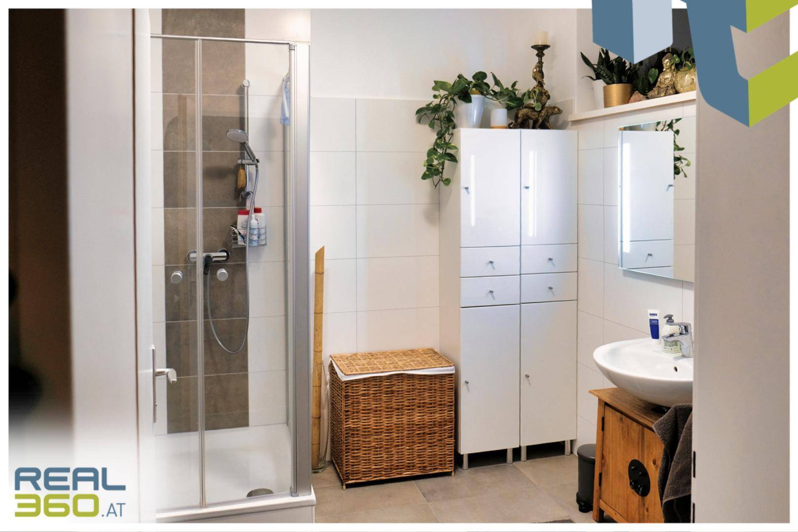 Helles Badezimmer mit Duschkabine, modernem Waschtisch und praktischem Stauraum.