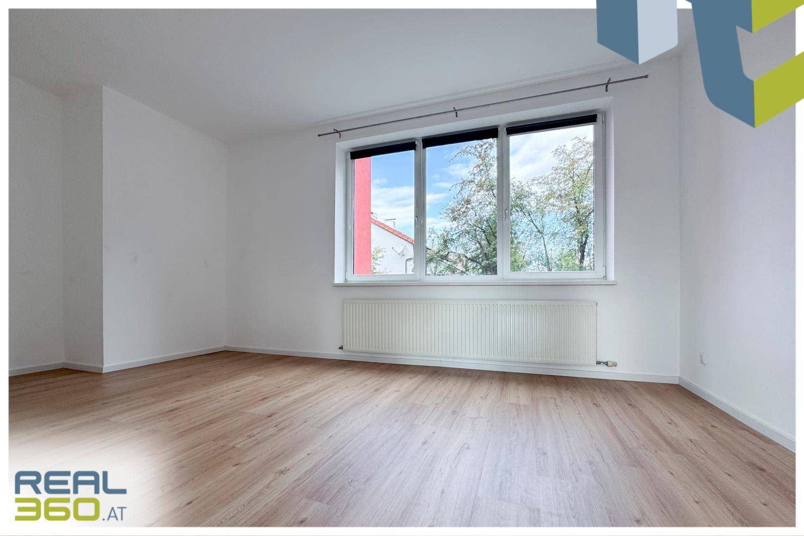 Helles Schlafzimmer mit Laminatboden und großem Fenster, ideal für eine ruhige Atmosphäre.