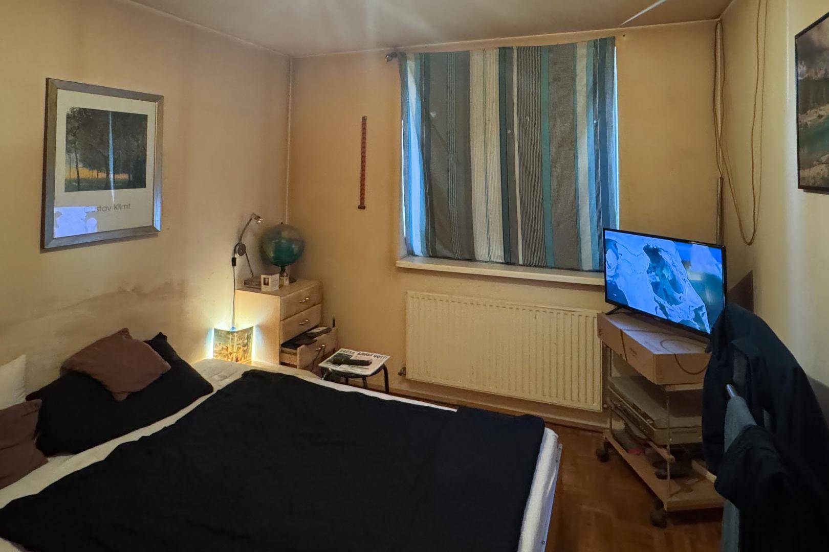 Gemütliches Schlafzimmer mit Bett, Fernseher und Fenster, das eine entspannte Atmosphäre schafft.