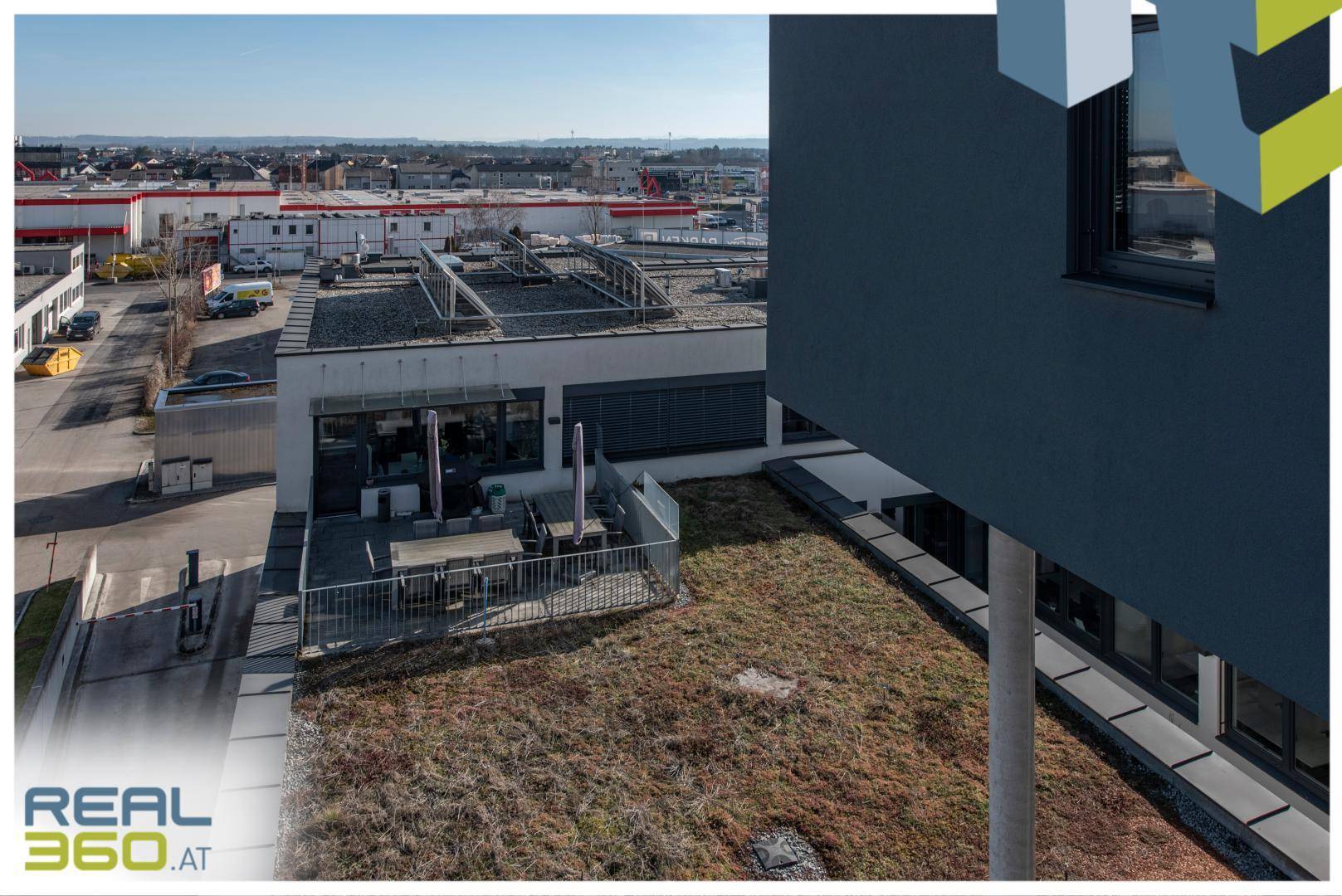 Dachterrasse mit Sitzbereich und Blick auf die umliegende Stadtlandschaft und begrünte Dächer.
