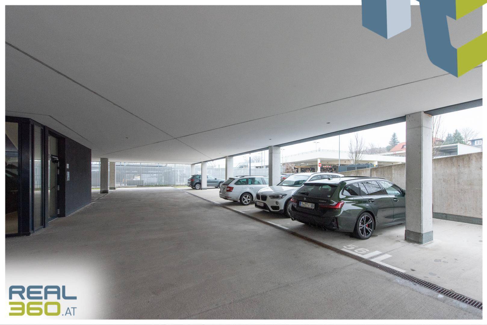 Überdachter Parkbereich mit mehreren Stellplätzen und Betonpfeilern, bietet Schutz vor Witterung.