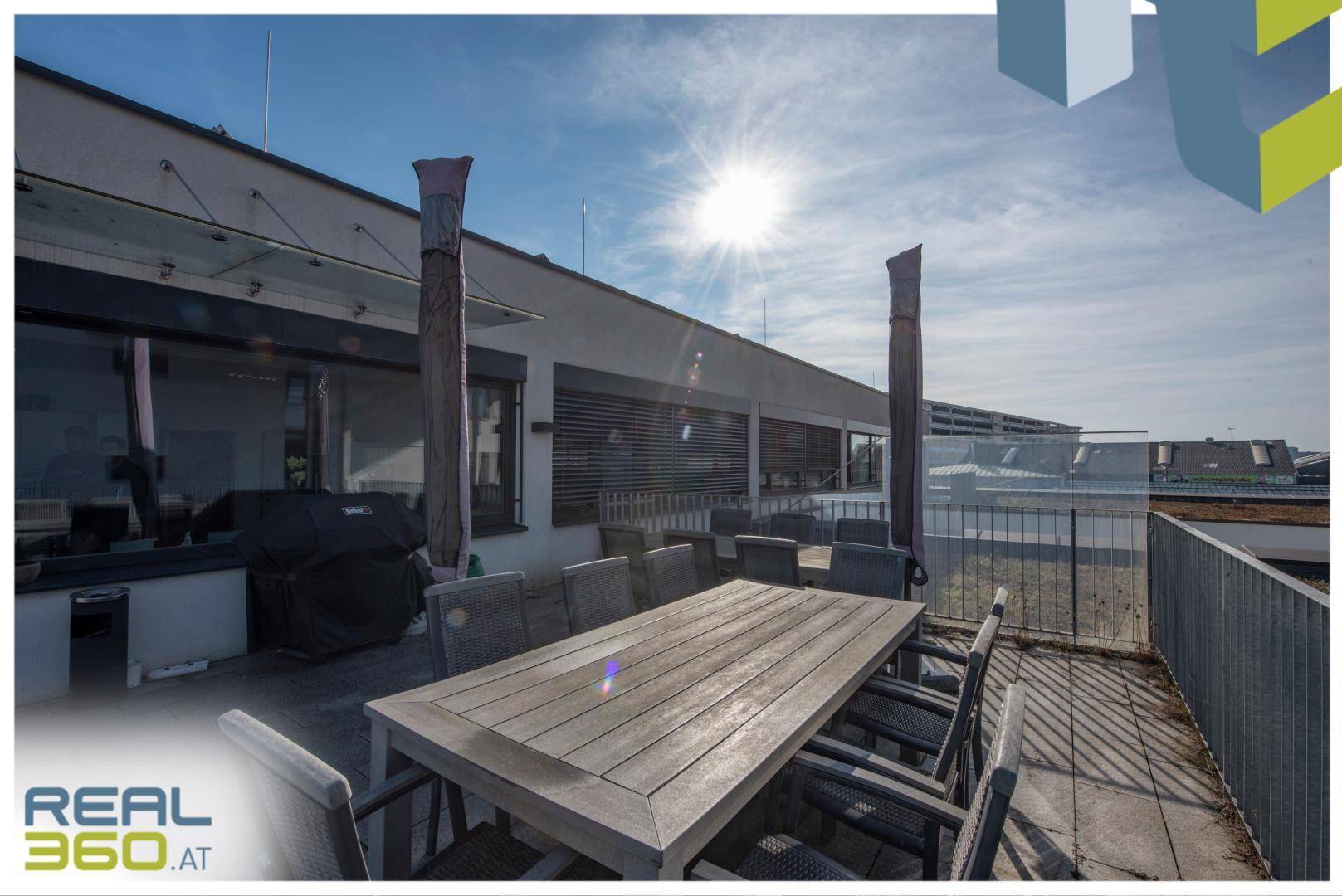 Sonnige Dachterrasse mit großem Holztisch, Stühlen und Grill, perfekt für Entspannung im Freien.