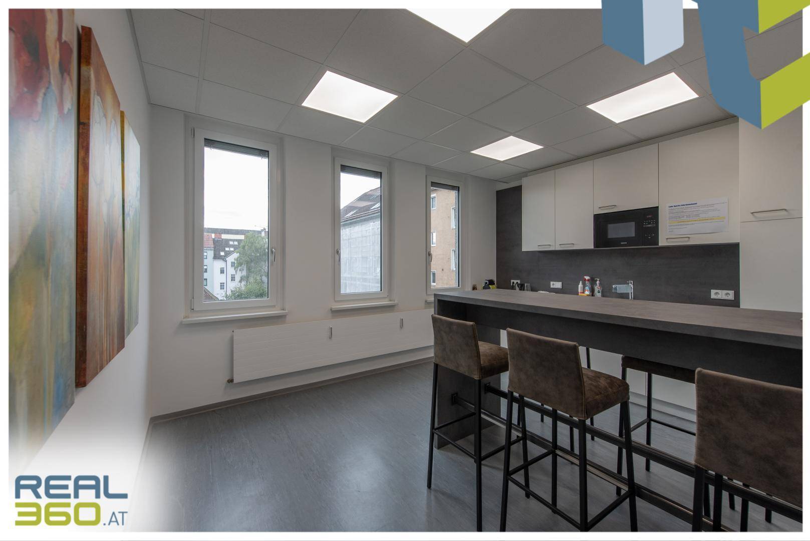 Moderne Küche mit Essbereich, Barhockern und großen Fenstern, die viel Licht hereinlassen.