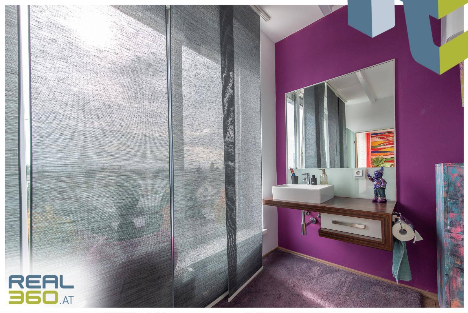 Waschraum mit großem Fenster, modernem Waschbecken und farbenfroher Wand.