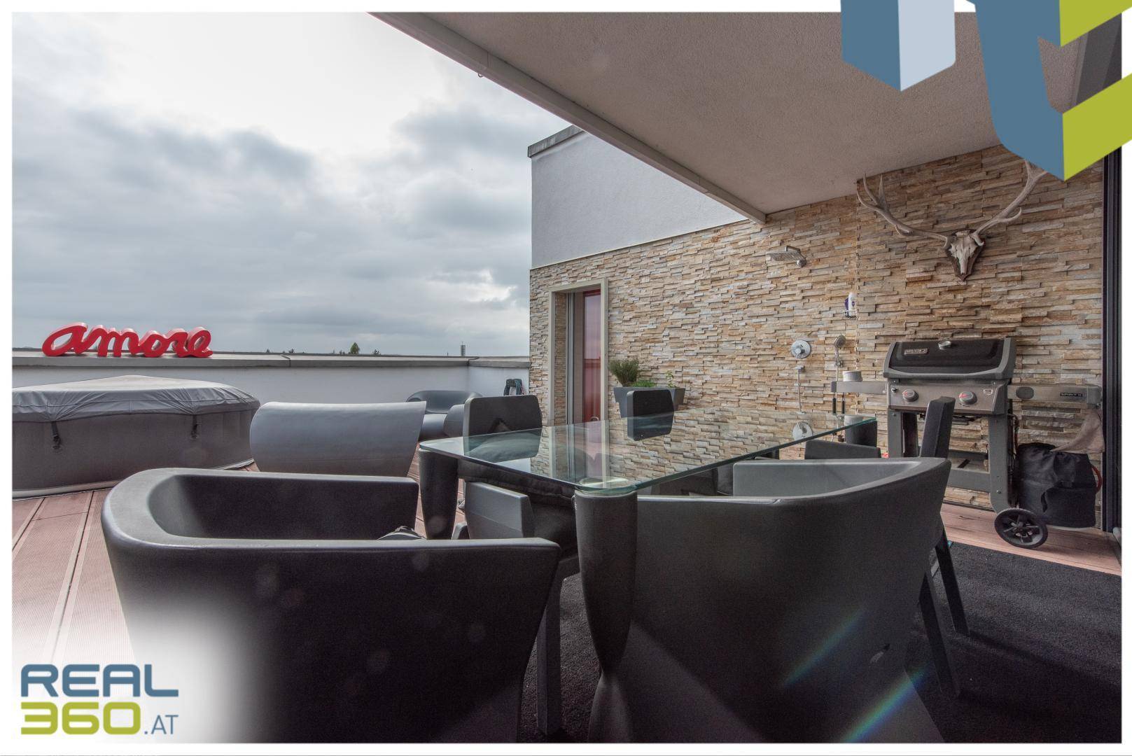 Gemütlicher Essbereich auf der Dachterrasse mit Grillstation und Steinwand.