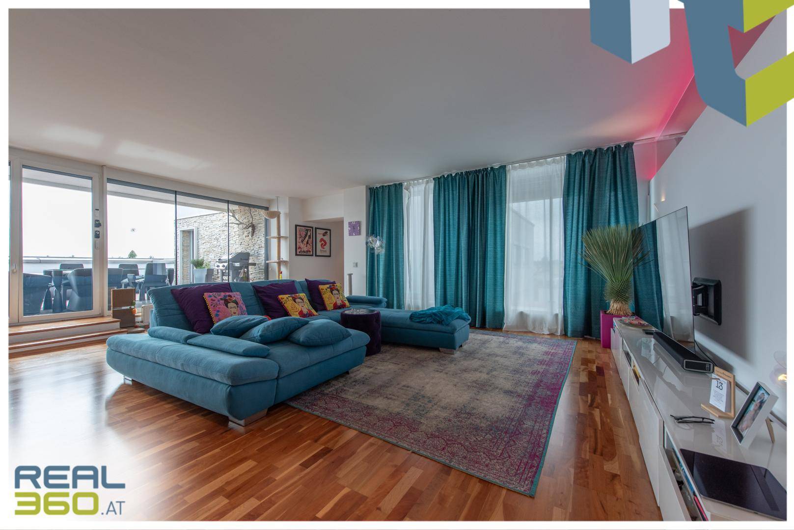 Geräumiges Wohnzimmer mit bequemer Couch, Parkettboden und großen Fenstern zur Terrasse.