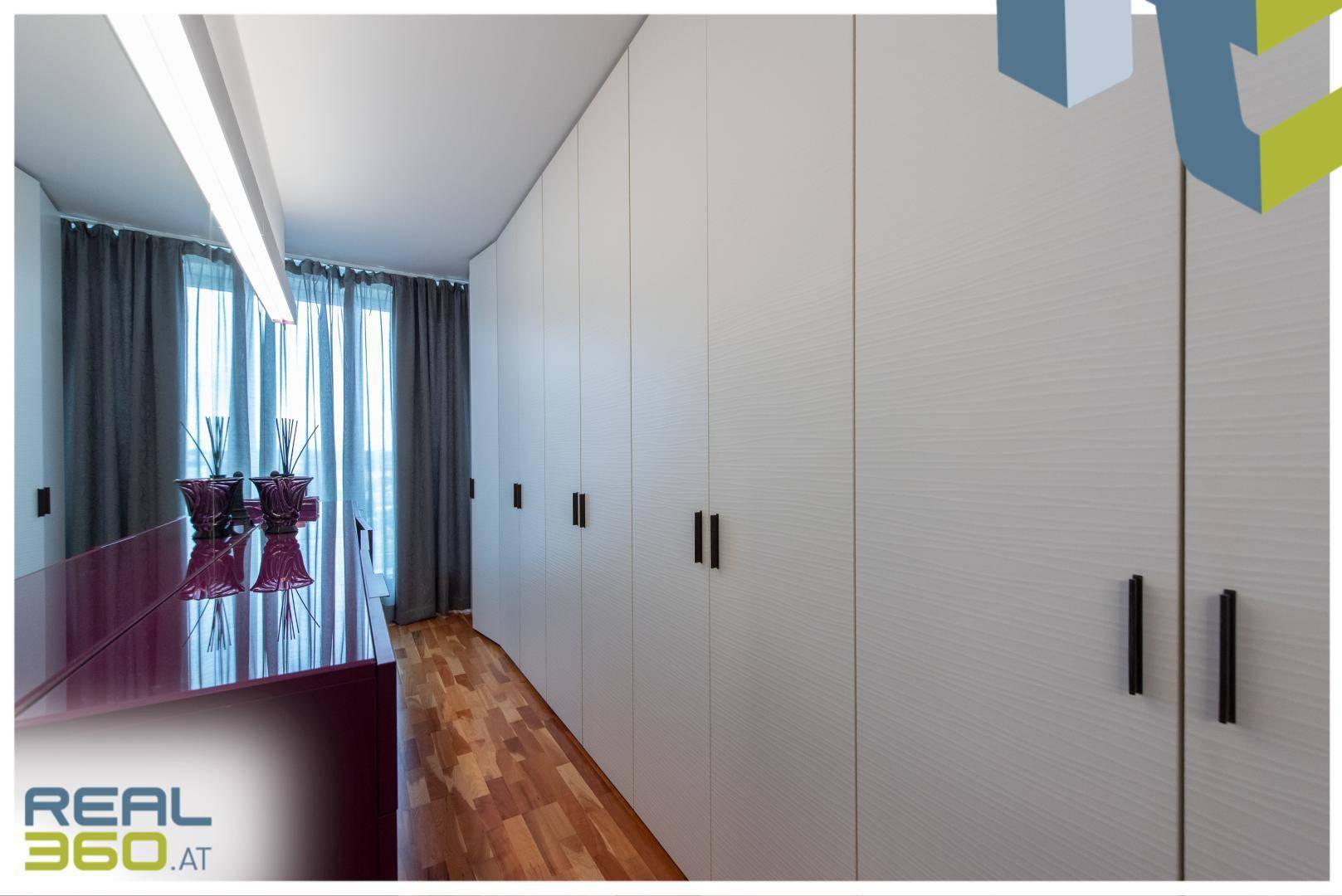 Geräumiger begehbarer Kleiderschrank mit vielen Einbauschränken und Parkettboden.