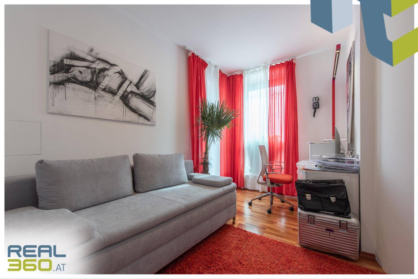Helles Arbeitszimmer mit Sofa, Schreibtisch und roten Vorhängen, ideal für Home-Office.