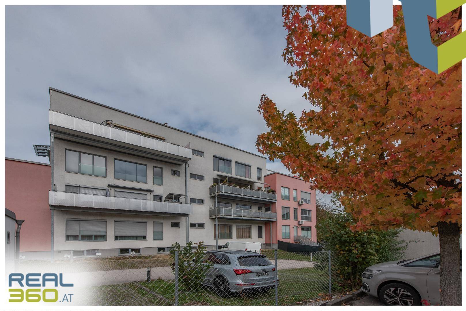 Modernes Mehrfamilienhaus mit Balkonen und gepflegter Außenanlage im Herbst.