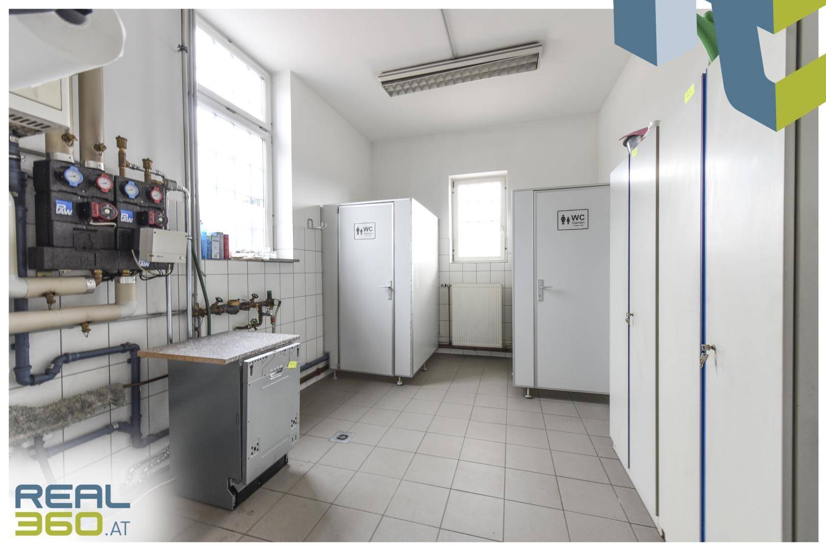 Sanitärbereich mit mehreren WC-Kabinen, Fliesenboden und einem Fenster für natürliche Belüftung.