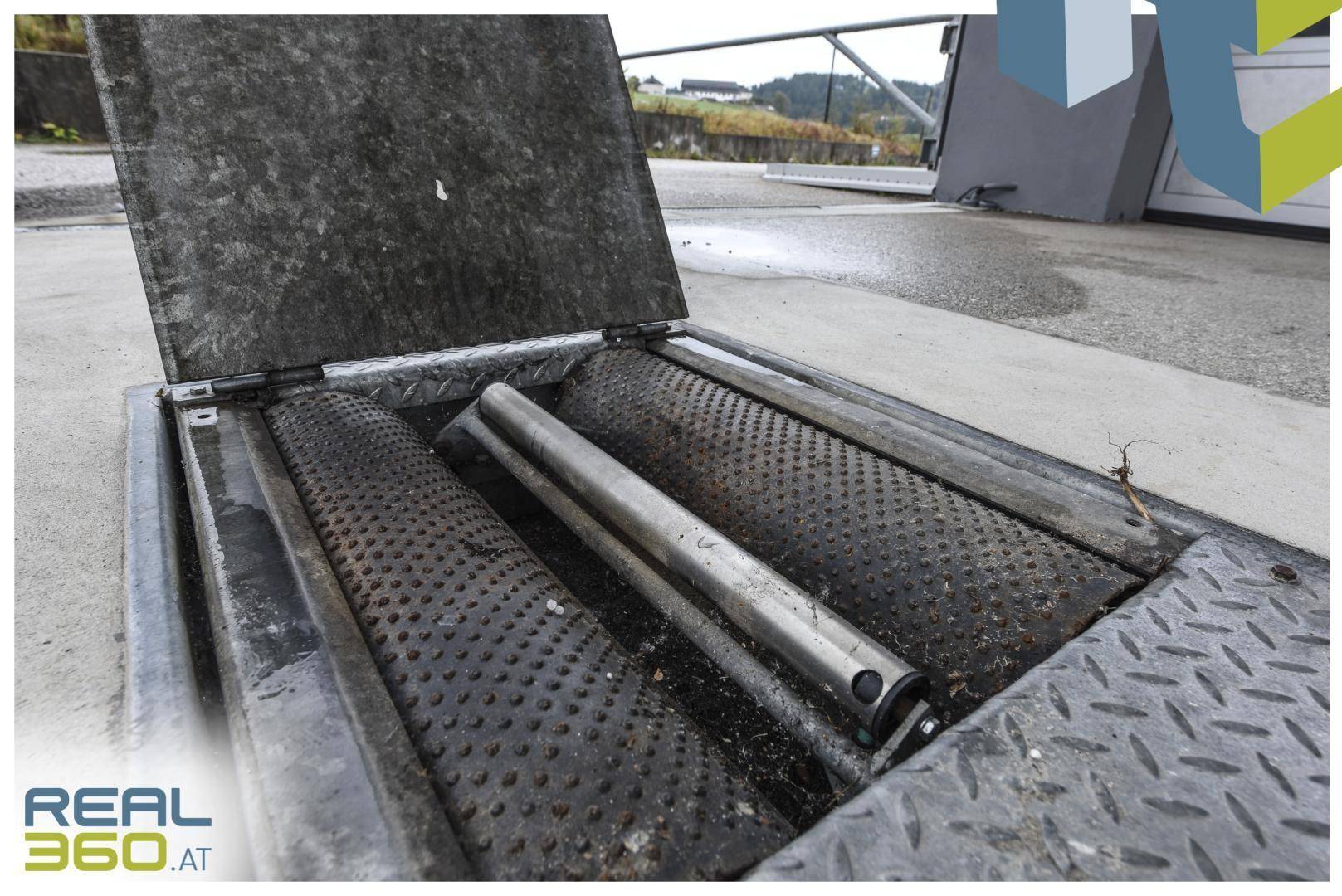 Bodeneingelassene Prüfvorrichtung mit Rollen und Metallabdeckung in einem Werkstattbereich.