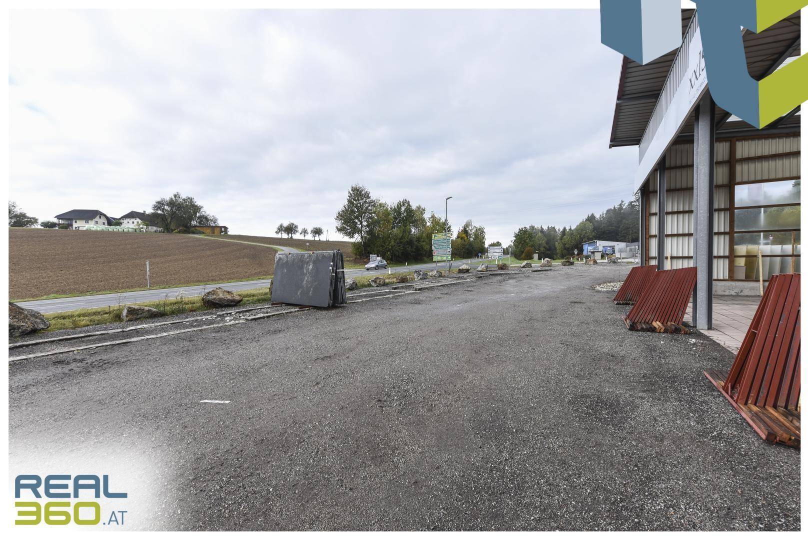 Großer Schotterparkplatz mit gelagerten Steinplatten und Blick auf die umliegende Landschaft.
