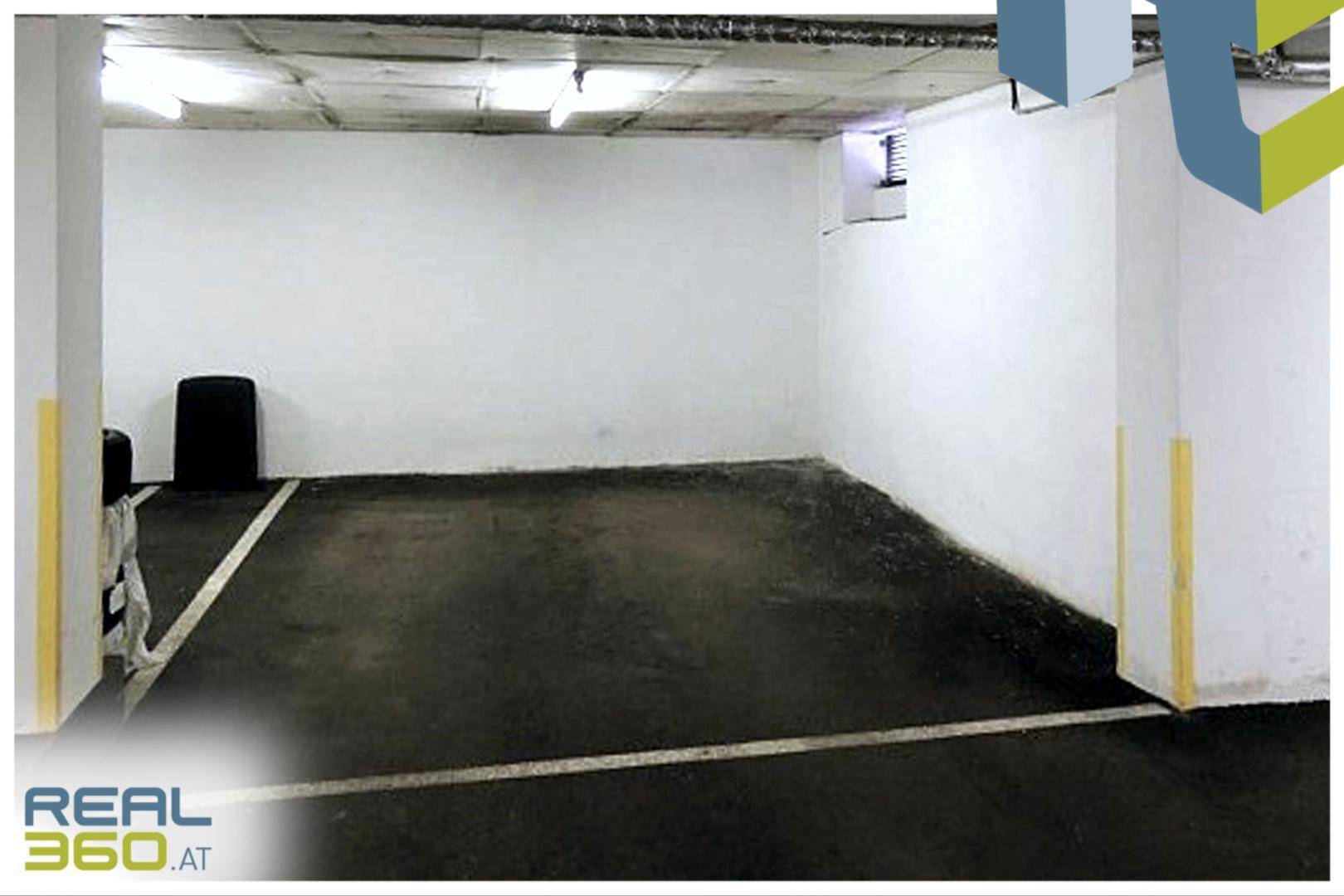 Leere Tiefgarage mit markierten Stellplätzen und Beleuchtung.