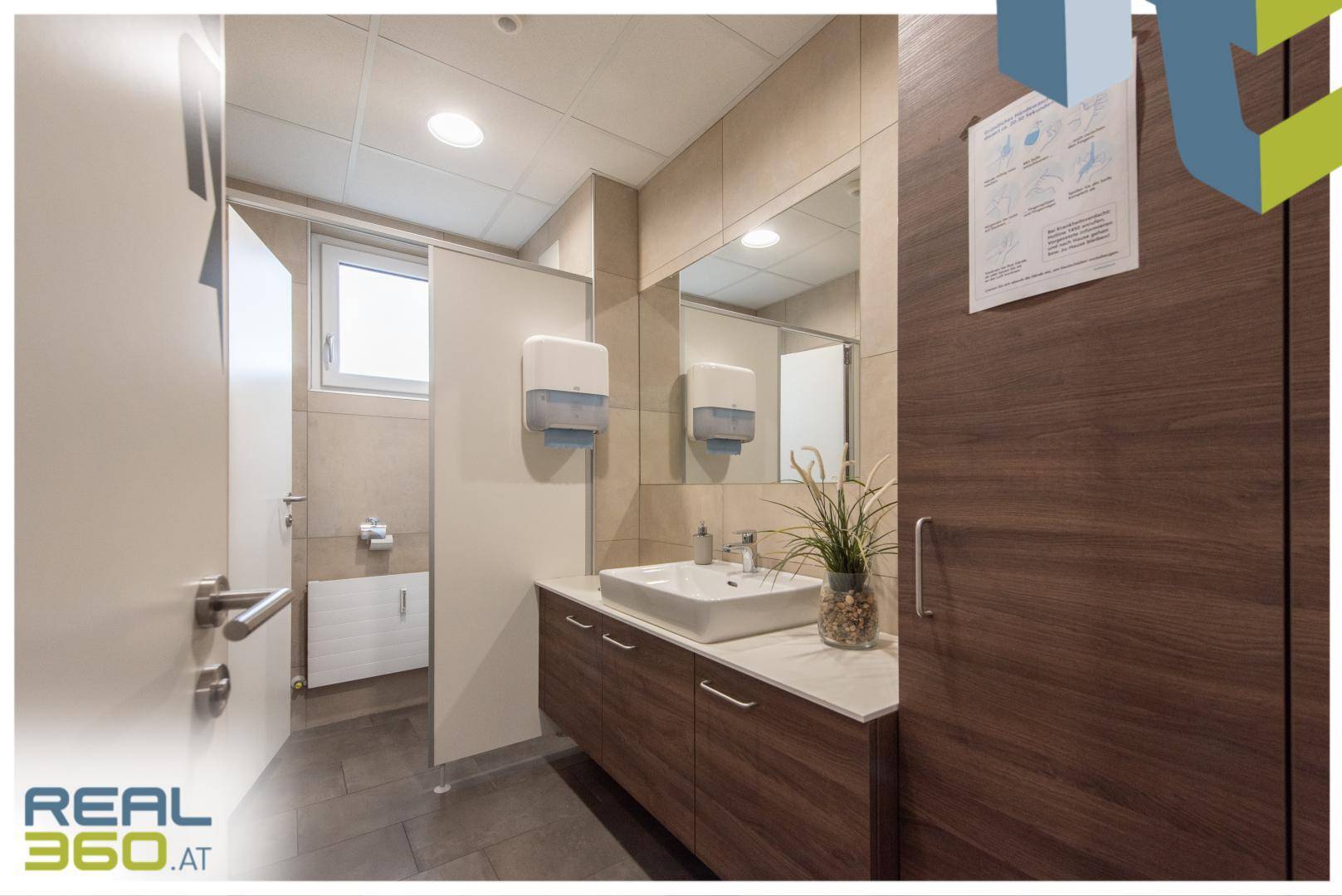 Modernes Badezimmer mit zwei Waschbecken, Holzunterschränken und beigen Fliesen an den Wänden.