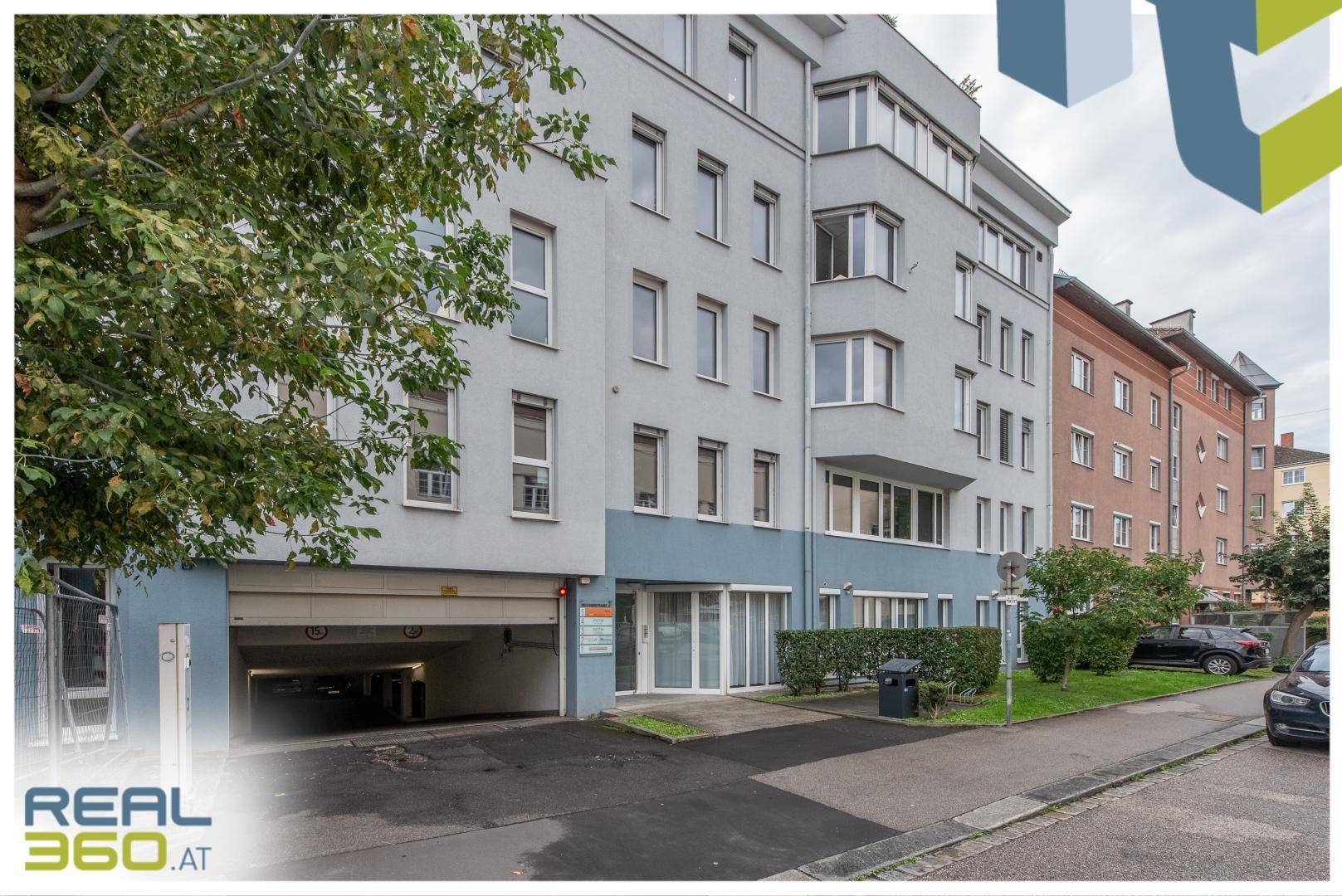 Modernes Bürogebäude mit mehreren Etagen, großen Fenstern und einer Tiefgarageneinfahrt.