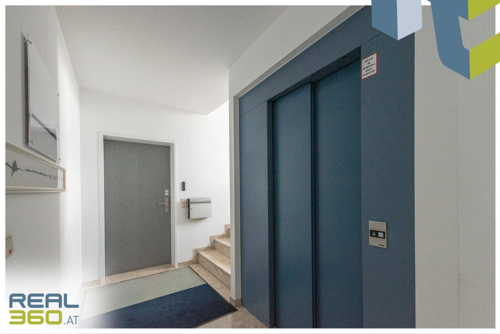 Eingangsbereich mit Aufzug und Treppe, die zu den oberen Etagen führt.