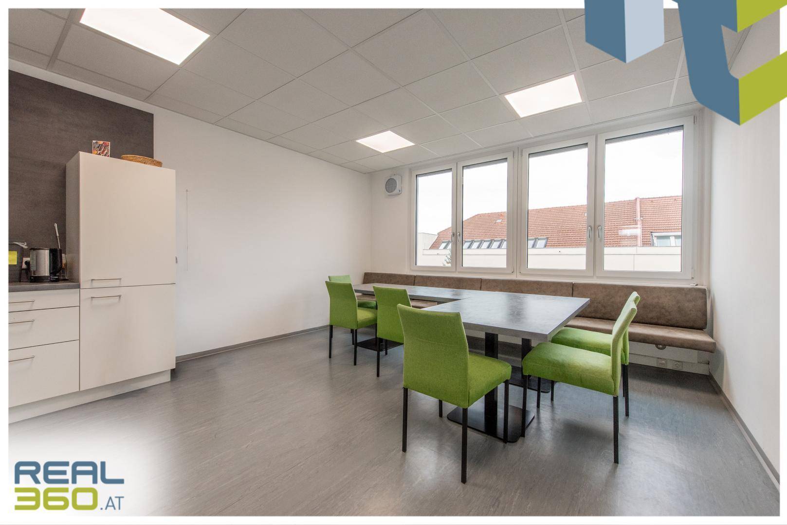 Große Essküche mit langer Tafel, grünen Stühlen und einer bequemen Sitzbank am Fenster.
