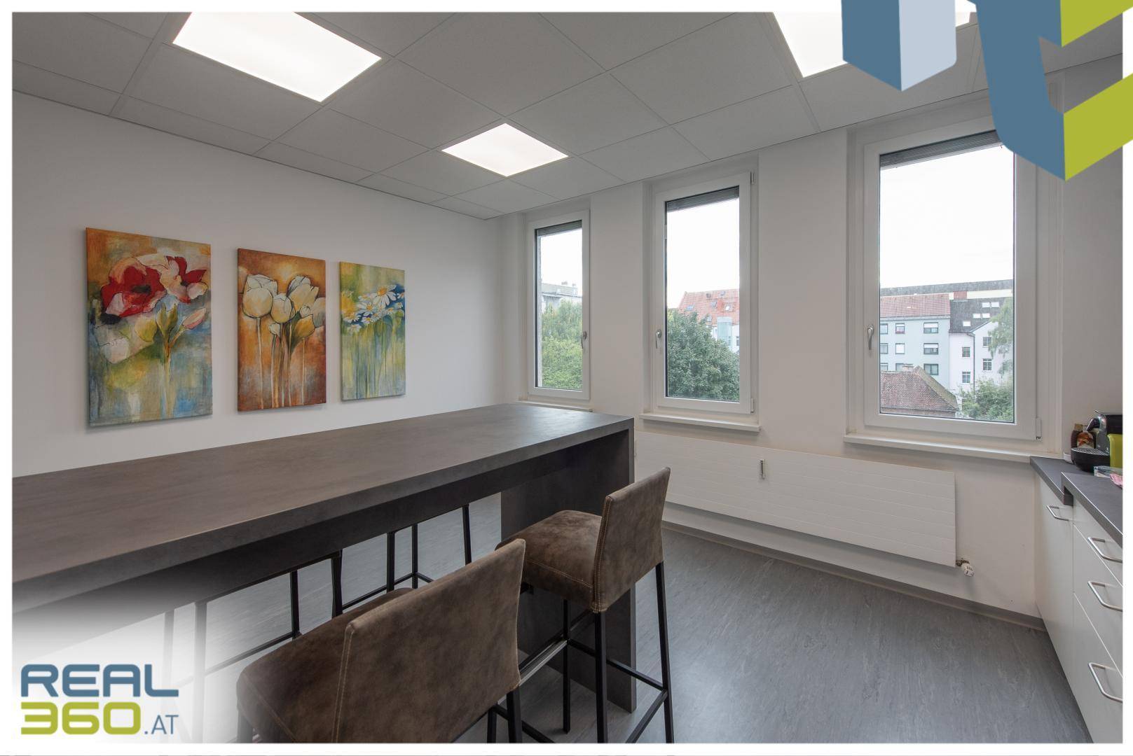 Moderne Küche mit Barhockern, Kunstwerken an der Wand und Fenstern mit Blick auf die Umgebung.