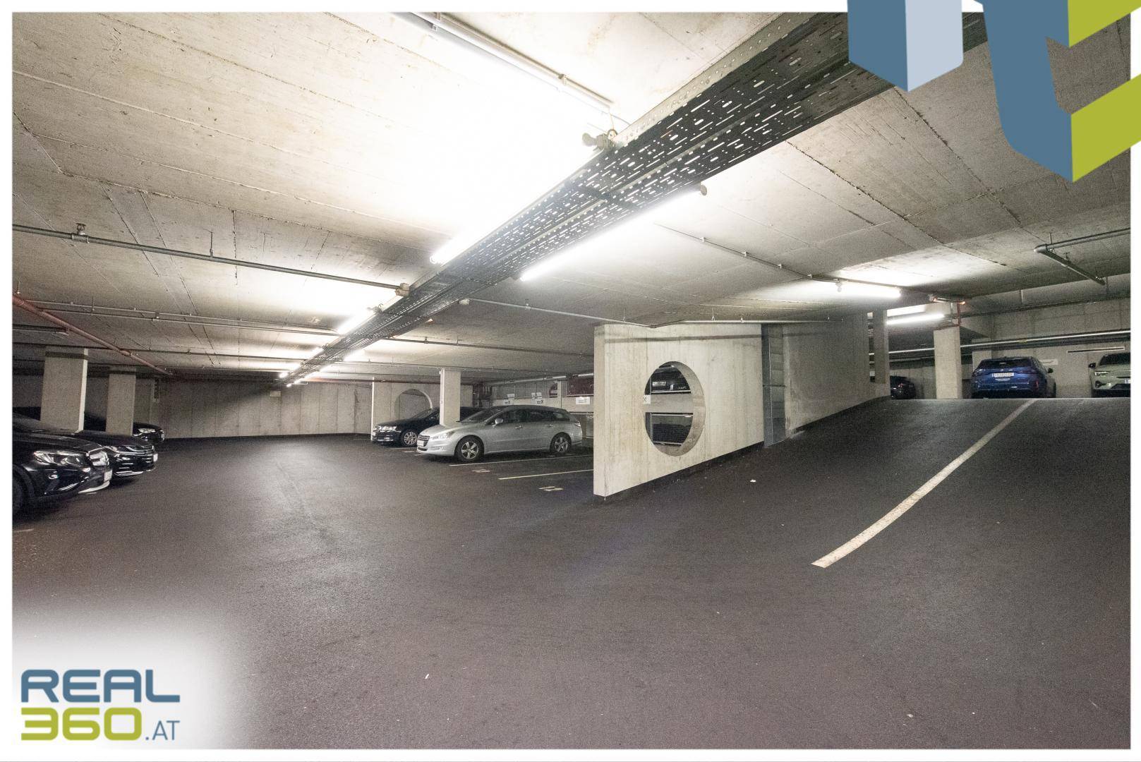 Geräumige Tiefgarage mit mehreren geparkten Autos und Betonwänden.