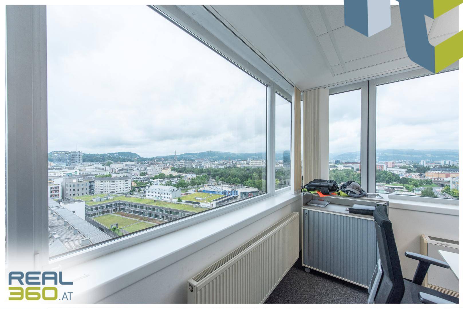 Heller Büroraum mit großen Fenstern, die einen weiten Blick über die Stadt bieten.