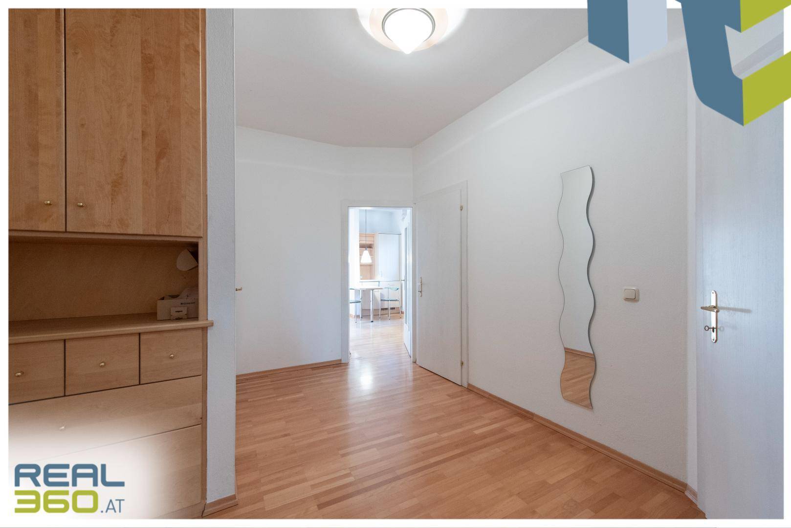 Heller Flur mit Parkettboden, Einbauschrank und dekorativem Spiegel.