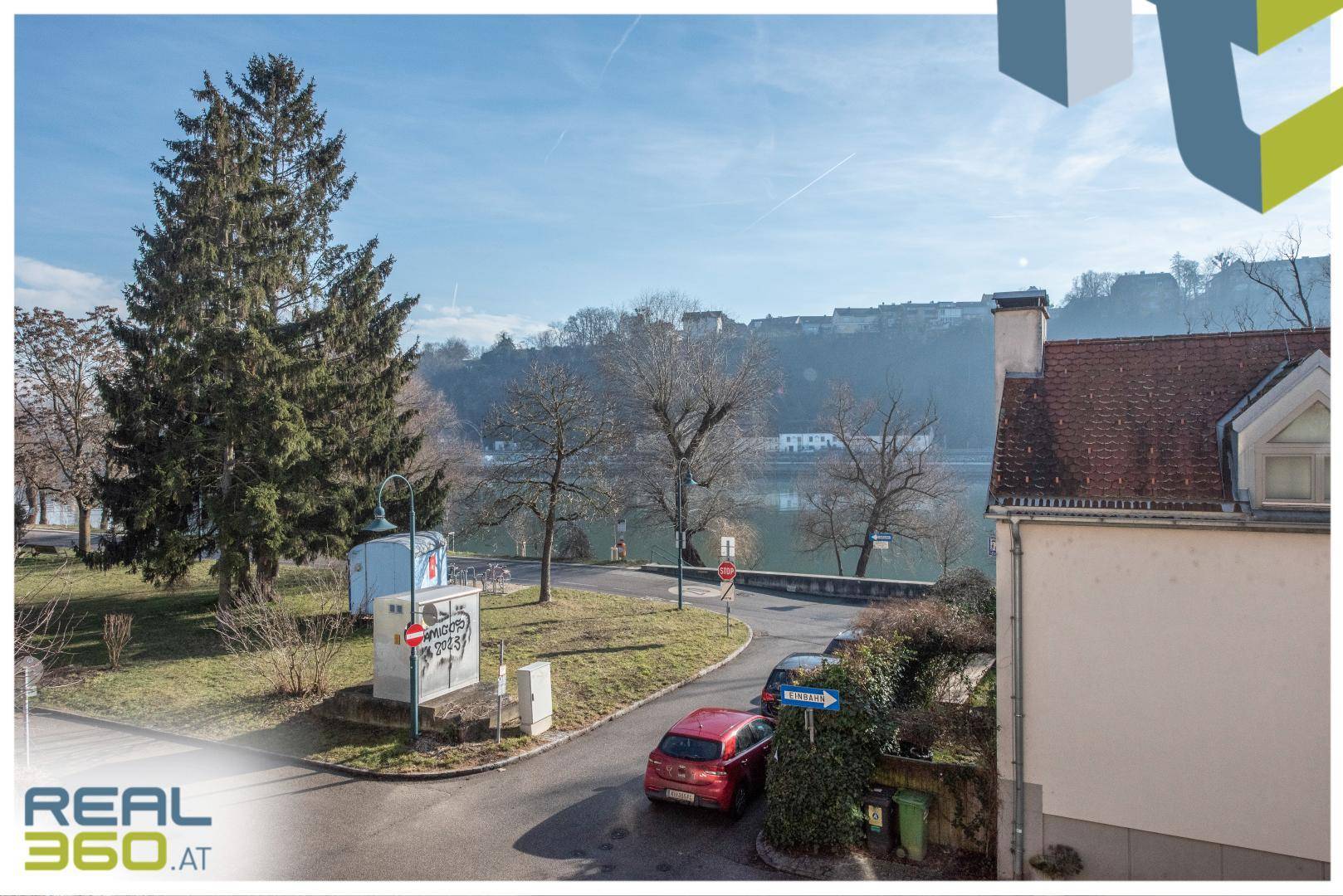 Blick auf die Umgebung mit Bäumen, Straße und einem Fluss im Hintergrund.