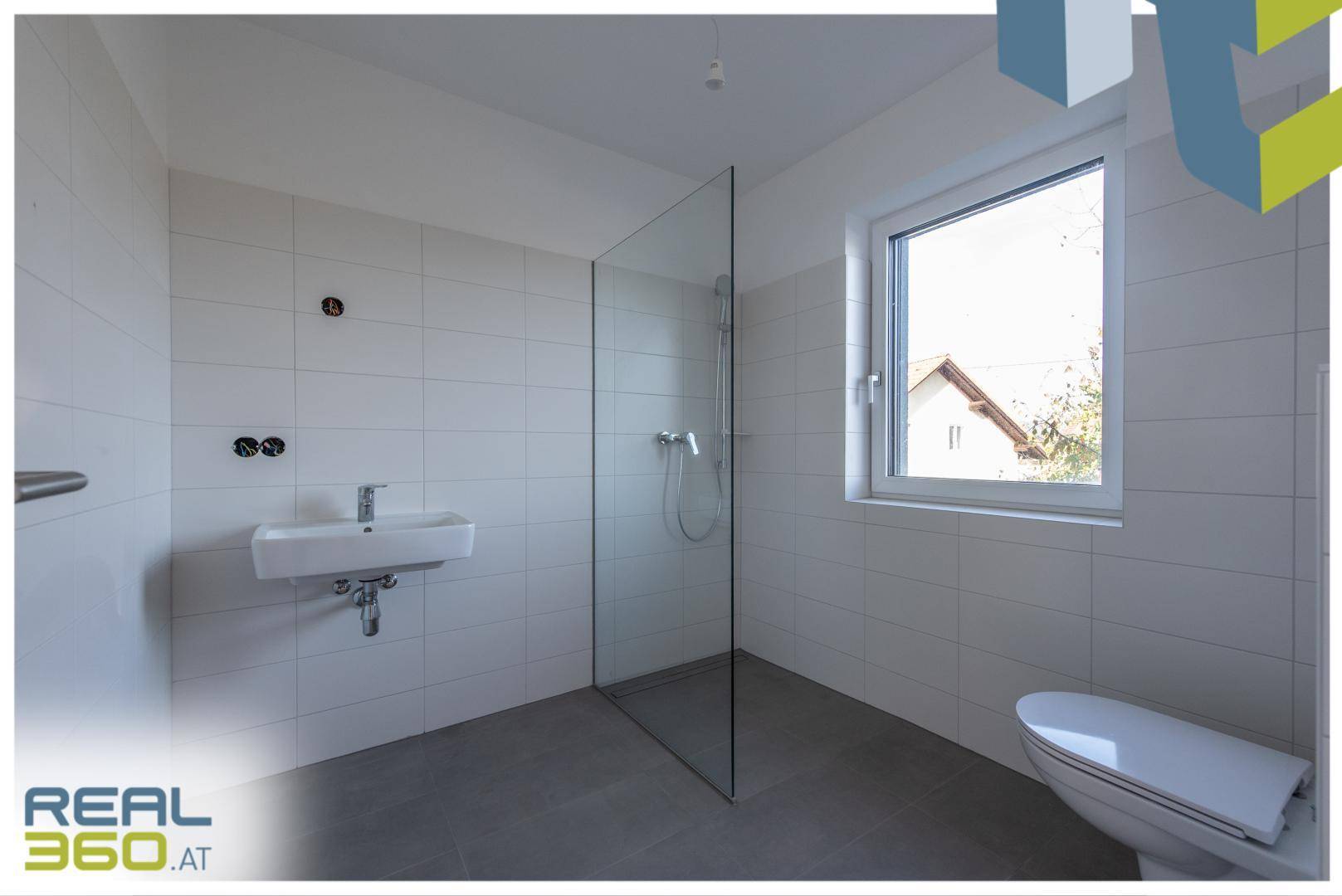 Modernes Badezimmer mit ebenerdiger Dusche, WC und Waschbecken.