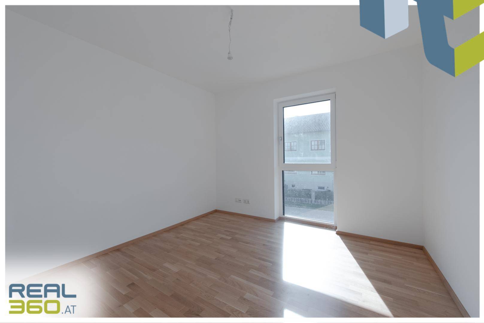 Geräumiges Zimmer mit Holzboden und großem Fenster für viel Tageslicht.