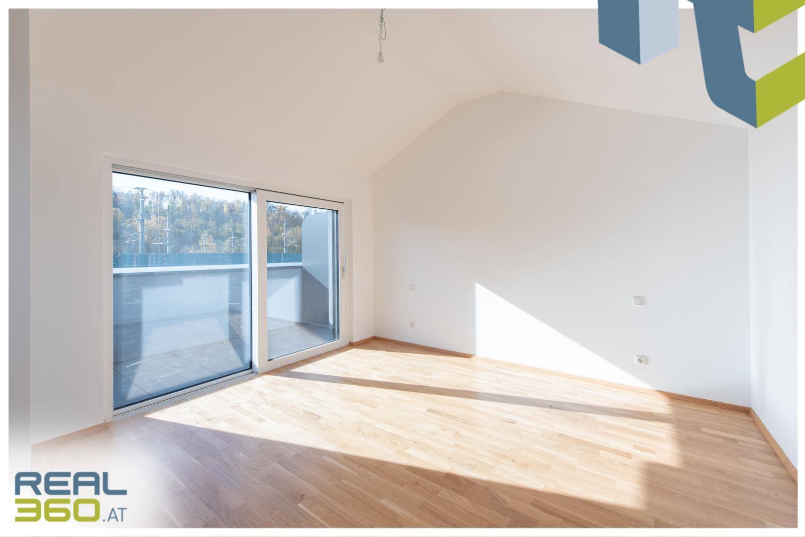 Helles Schlafzimmer im Dachgeschoss mit Holzboden und Zugang zum Balkon.