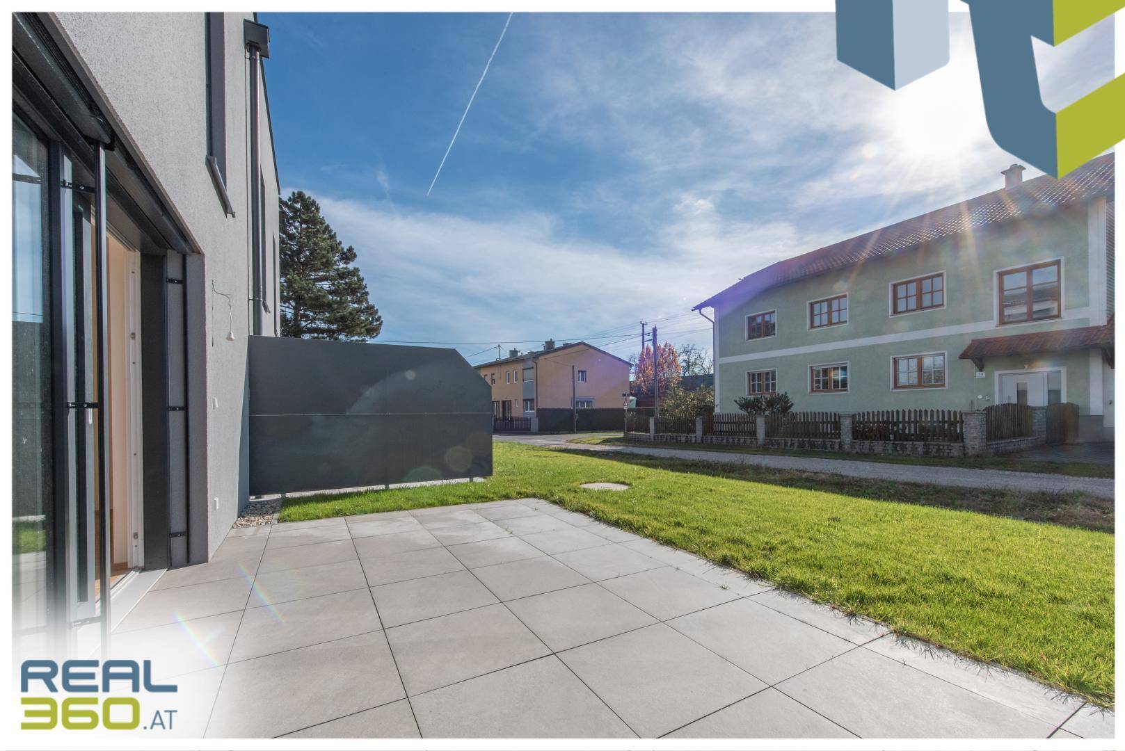 Sonniger Terrassenbereich mit Fliesenboden und Blick auf die Nachbarschaft.