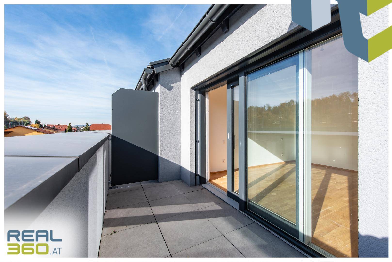 Sonniger Balkon mit Fliesenboden und Blick auf die Umgebung.