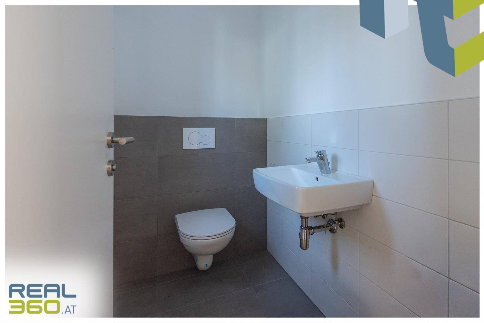 Modernes Gäste-WC mit Wand-WC, Waschbecken und zweifarbigen Fliesen.