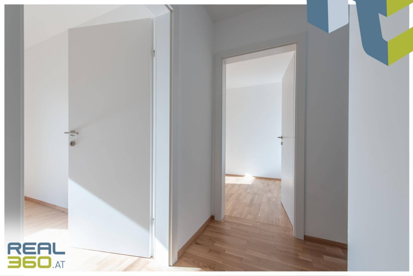 Heller Flur mit Holzboden und mehreren Türen zu angrenzenden Räumen.