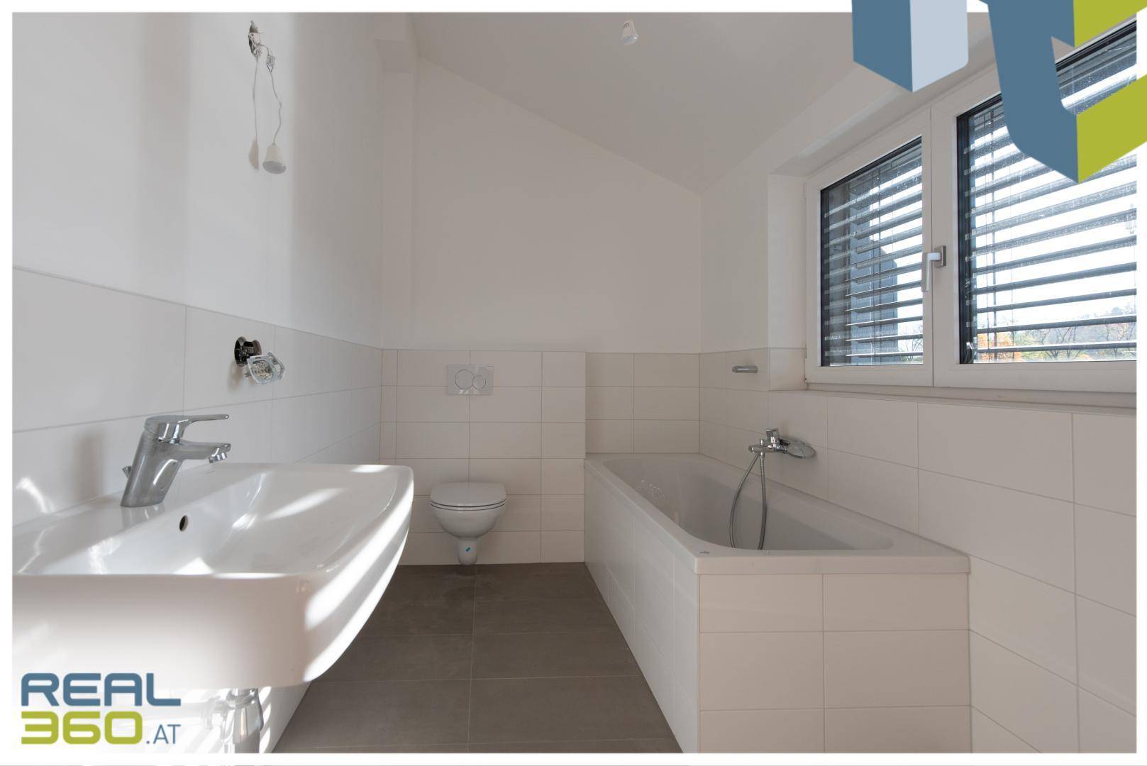 Badezimmer im Dachgeschoss mit Badewanne, WC, Waschbecken und Fenster.