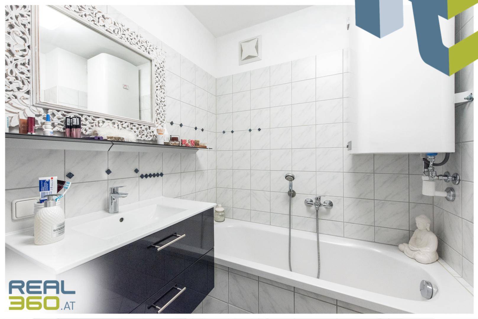Badezimmer mit Badewanne, Waschbeckenunterschrank und weiß gefliesten Wänden.